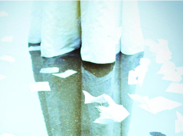 The hem of a wedding gown, reflected in a puddle - blank pages floating around