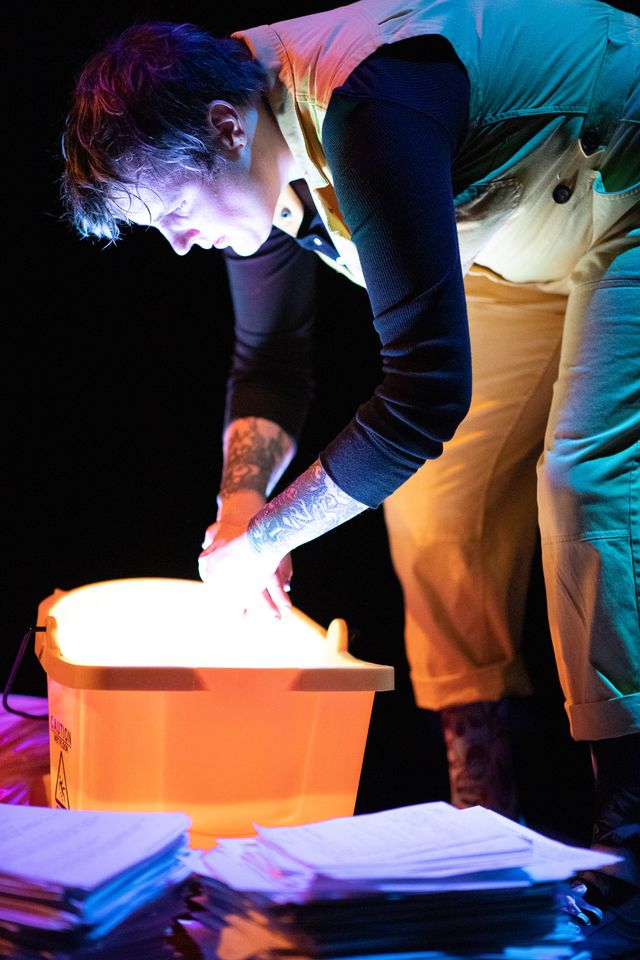 Miriam leans over to wash her hands in a glowing yellow mop bucket