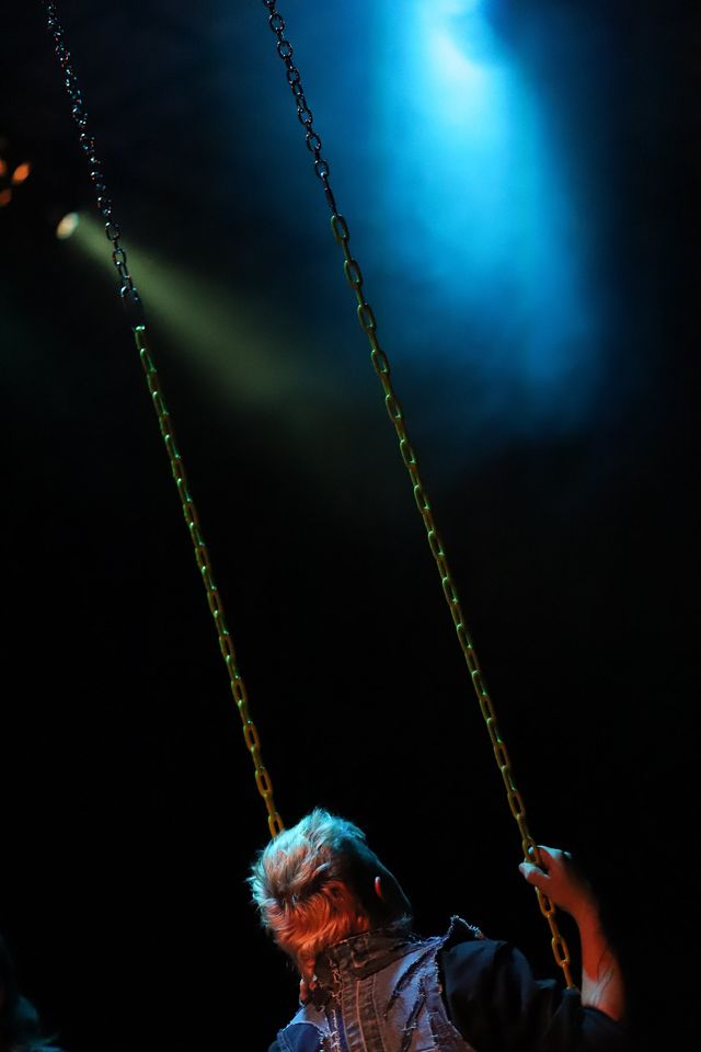 A bower bird dancer swings in a haze of blue light