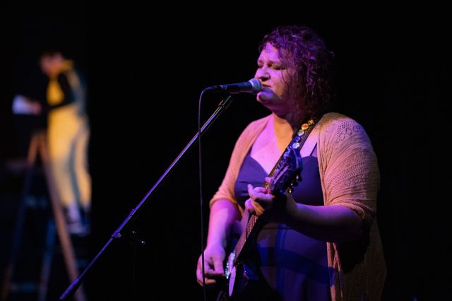 Josie sings and plays guitar, with Miriam blurry in the back on a ladden